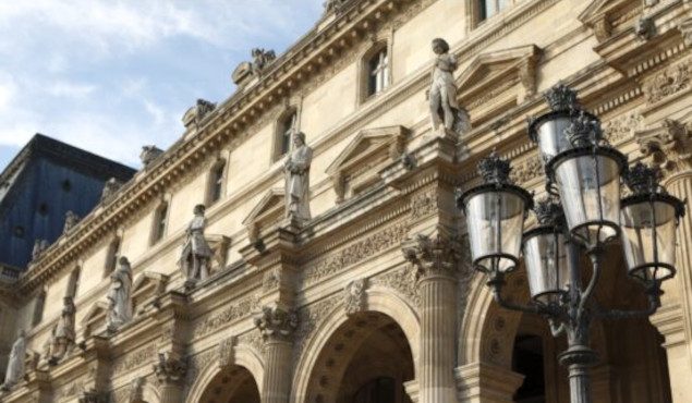 Renaissance architecture and street lamp at the Louvre Museum in Paris bathed in warm late afternoon light.